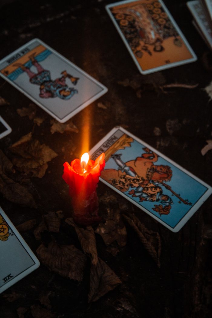 Close-up of tarot cards with a burning candle creating a mystical atmosphere.